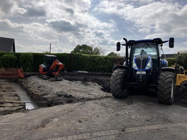 Foundation trench and compacted gravel, with a tractor and mini digger on site